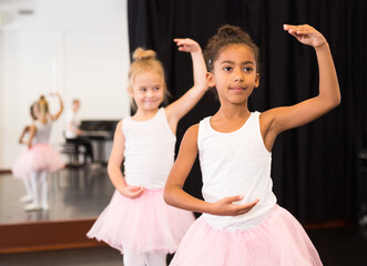 Portrait of two little ballerinas practicing choreography in dance hall