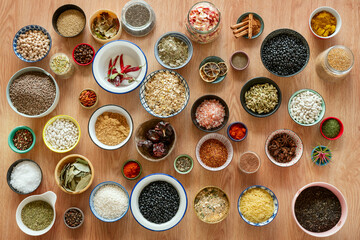 Set of bowls filled with all kinds of seasonings and legumes seen from the top