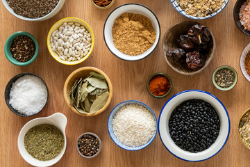 Set of bowls filled with all kinds of seasonings and legumes seen from the top