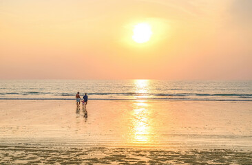 Family walking towards the sea on a Khao Lak beach.