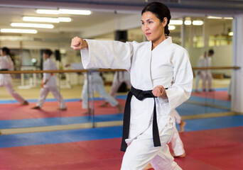 Portrait of asian female instructor wearing white kimono during training in gym © JackF