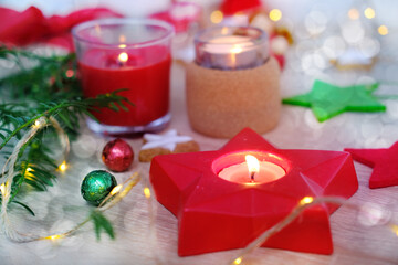 closeup decorated pre-Christmas table, candles are lit, garlands are lit, gift with red ribbon, concept of giving gifts to those close to holiday, festive mood, stars, sweets, cookies are scattered
