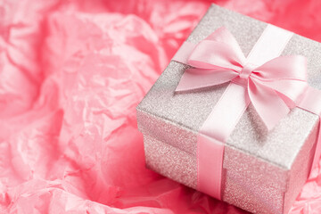 Silver glitter gift box with pink ribbon bow on pink background. Christmas, Valentine's day or birthday concept. Place for text.