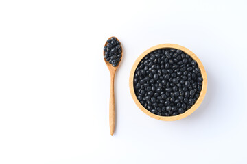 Black soy bean seeds in a wooden bowl with spoon on white background