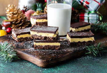 Fresh Nanaimo bars served with a glass of milk on a wooden board.