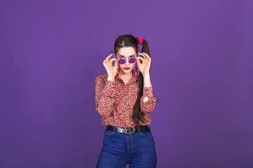 Pretty young woman in retro 90s fashion style over purple studio background