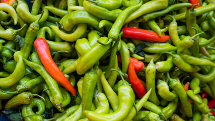 Close-up on a shelf with green and red peppers in the market.
