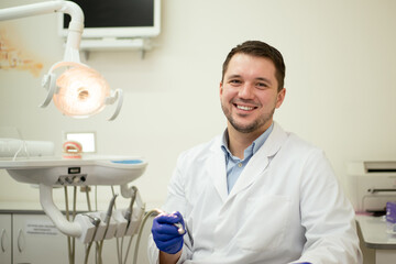 Male dentist smiling and holding tools in his hands. High quality photo