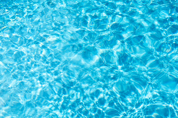 Fototapeta na wymiar Summertime background with turquoise textured water in swimming pool. Hot sunny vacation concept