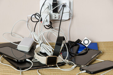 Sharing power: power adapter and power banks charging multiple devices in a messy cable connection - obrazy, fototapety, plakaty