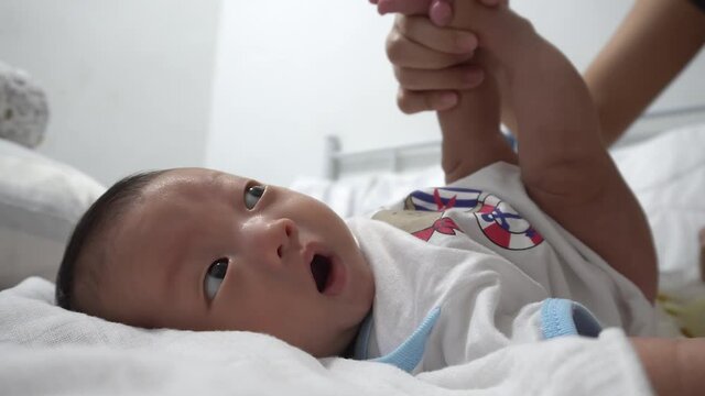 Mother raise the leg of newborn baby and clean the shit. New family member in house