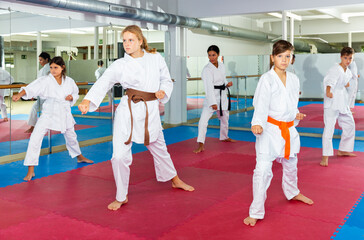 Focused children trying new martial moves in a practice during karate class in gym with their coach