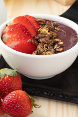 Frozen açaí with strawberry and granola in a white bowl.