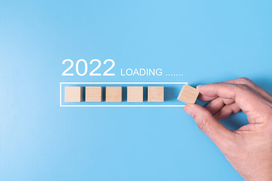 Loading new year 2022 with hand putting wood cube in progress bar