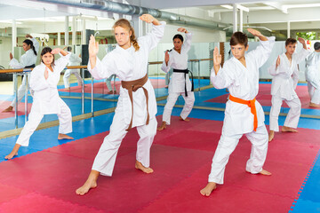 Focused children trying new martial moves in a practice during karate class in gym with their coach