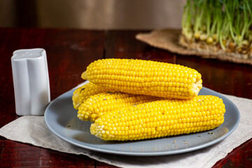 Sweet hot boiled corn on grey plate salt sprinkled 