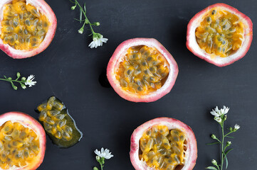 Purple passion fruit with cut in half. Passiflora edulis fruit and white flower on black background.