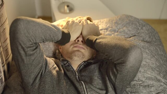 A young white man lies exhausted and tired on his bed. Close up of face