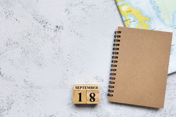 September 18th. Hello September, Cube wooden calendar showing date on 18 September, Wooden calendar with book on map.