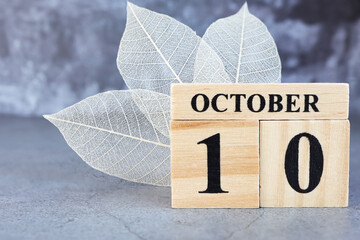October 10th. Hello October, Cube wooden calendar showing date on 10 October, Wooden calendar with date on a dark background.