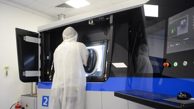 Person in white overalls works with machine with large rubber sleeves