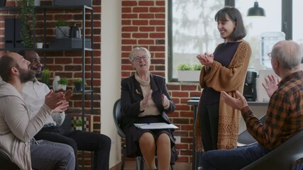 Happy adult celebrating recovery success with group of people clapping hands at aa meeting. Woman sharing achievement and progress at therapy, receiving applause from addiction patients.