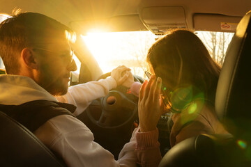 Man keeps woman hand at the wheel. Journey of two lovers in car. Riding at sunny day. View from rear seat. Road trip concept. Warm toned. Soft focus.