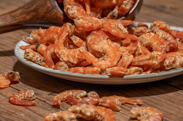 Shelled fresh shrimps on a plate or bowl are on a wood colored table