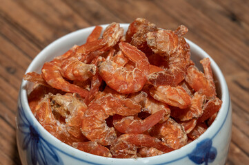 Shelled fresh shrimps on a plate or bowl are on a wood colored table