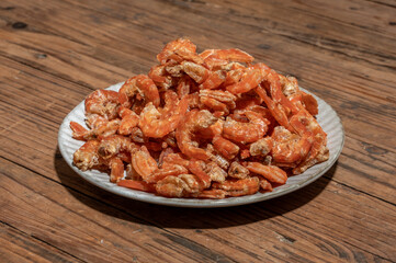 Shelled fresh shrimps on a plate or bowl are on a wood colored table