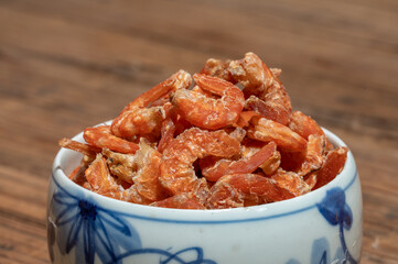 Shelled fresh shrimps on a plate or bowl are on a wood colored table