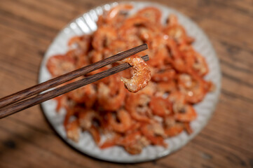 Shelled fresh shrimps on a plate or bowl are on a wood colored table