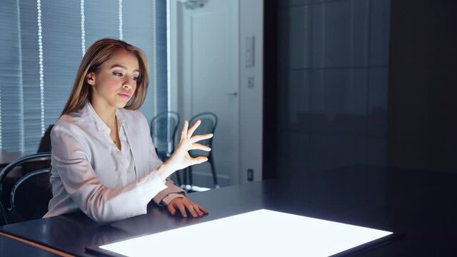 Hispanic woman watching a blight screen in the dark office. Stereoscopic vision. Heads up display.