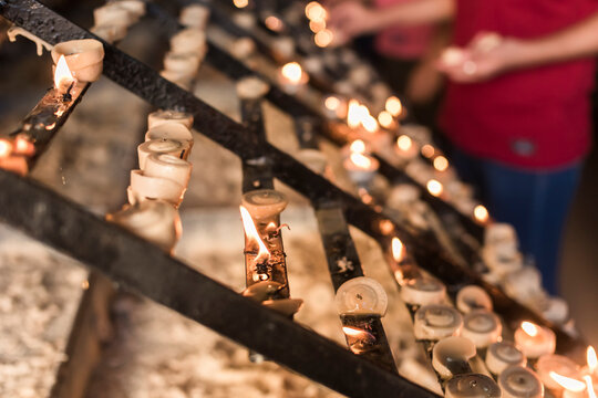 Devotees lighting and placing prayer candles on a rack at a chapel. Shot at Baclaran church, Philippines.