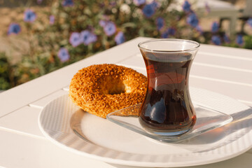 Crispy Turkish traditional bagel, simit with sesame and glass of turkish black tea, turkish breakfast pastry concept. Turkish tea in traditional glass cup. 