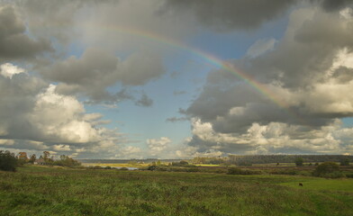 Fototapeta na wymiar Meadow with clouds and rainbow.