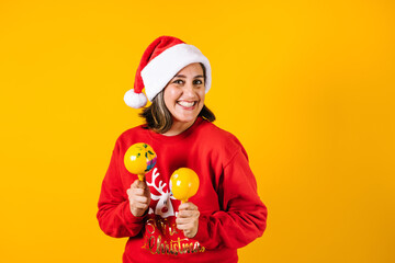 Portrait of Latin adult woman holding Christmas gift box on a yellow background in Mexico latin america
