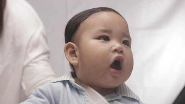 Cute Baby Boy With Chubby Cheeks Playing With White Plastic Bottle. close up