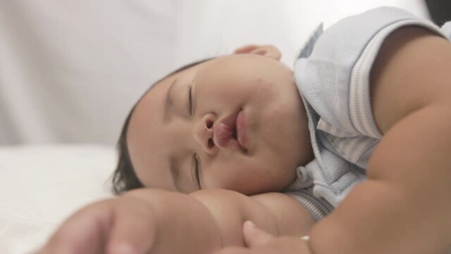Chubby Baby Boy Peacefully Sleeping On The Bed. - close up
