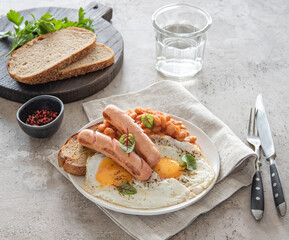 Traditional English breakfast with fried eggs, sausages, beans, fresh herb, red pepper and toast on a gray background. Concept morning food