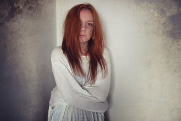 A girl with red hair in a shirt. Domestic violence and sacrifice. Girl with a sick psyche.