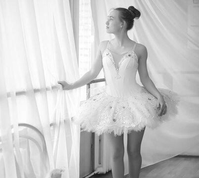 Young ballet dancer on a warm-up. The ballerina is preparing to perform in the studio. A girl in ballet clothes and shoes kneads by the handrails.