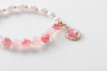 pink and white bracelet made of natural stones on white background