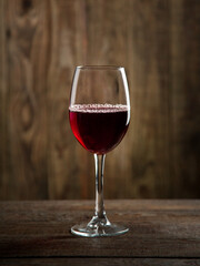 A glass of red wine on a wooden table with a wooden background