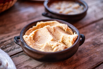 Hummus in clay bowl on wooden table