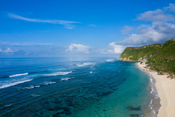 Fototapeta na wymiar Aerial drone landscape view of the white sand beach of Melasti located in South Bali in Indonesia, with tidal waves breaking along the shoreline.