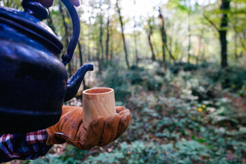 A man holds a traditional wooden Kuksa mug. Autumn forest, close-up.