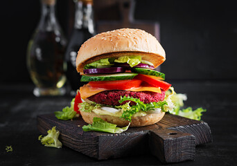 Healthy vegan beetroot burgers with tomato, cucumber, red onion and sauce. Dark background. Copy space.