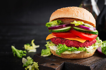 Healthy vegan beetroot burgers with tomato, cucumber, red onion and sauce. Dark background. Copy space.