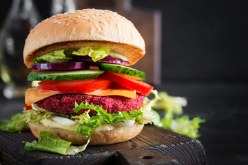 Healthy vegan beetroot burgers with tomato, cucumber, red onion and sauce. Dark background. Copy space.